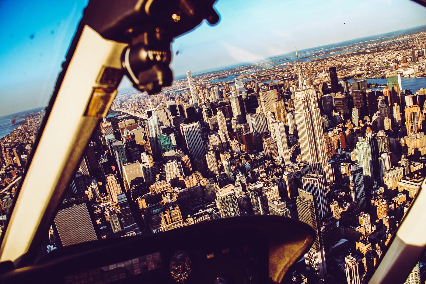 HeliNY green Bell 407 helicopter parked at East River heliport with Midtown Manhattan skyline