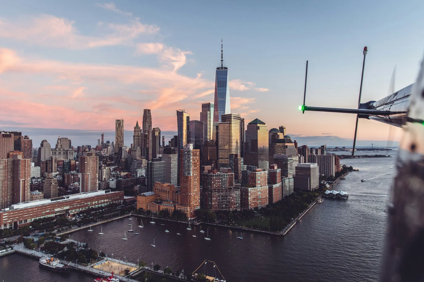 Sunset over Manhattan from a helicopter cabin with rotor blade in frame